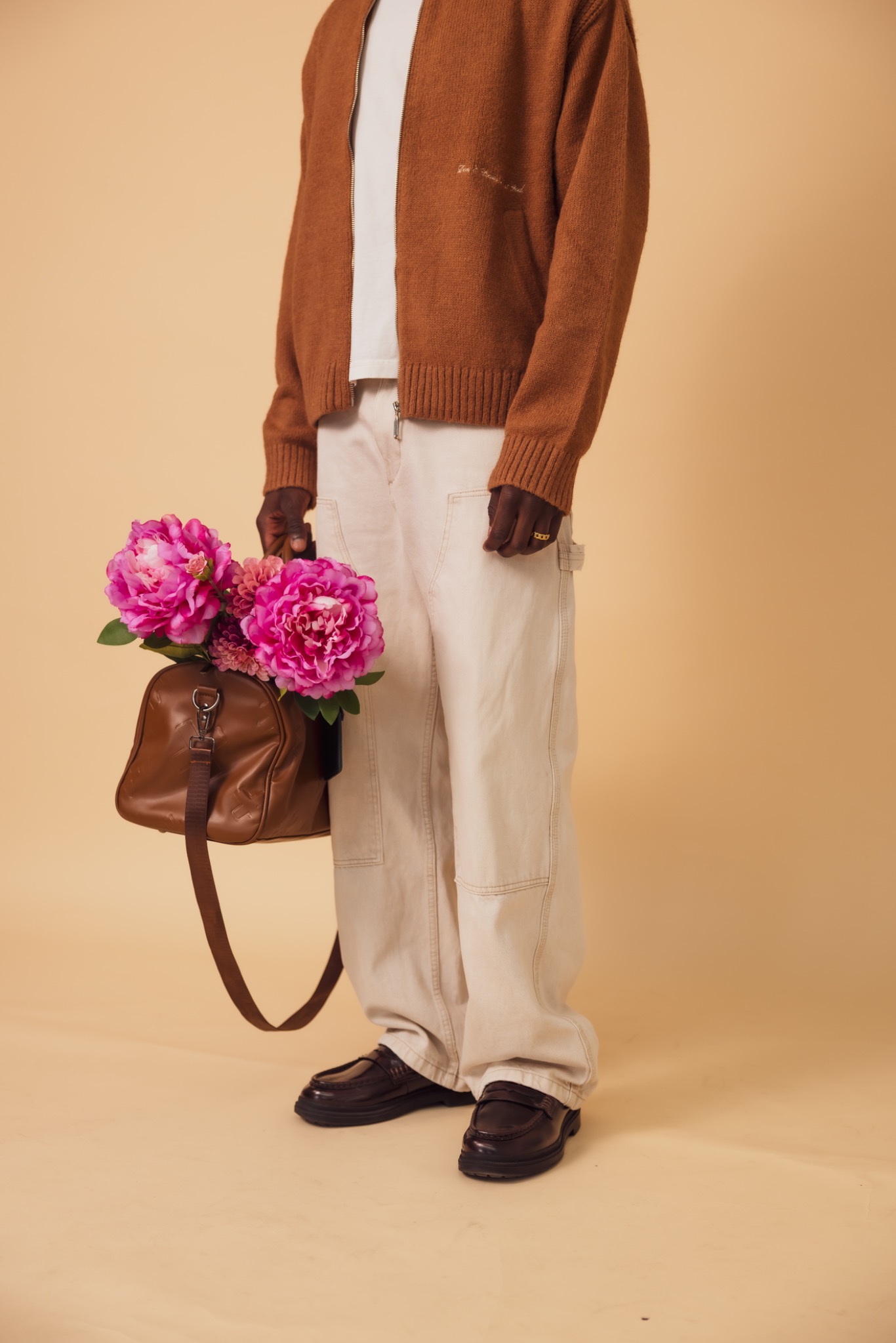 VERITÉ Camel zip-up campaign, holding a brown bag with pink flowers