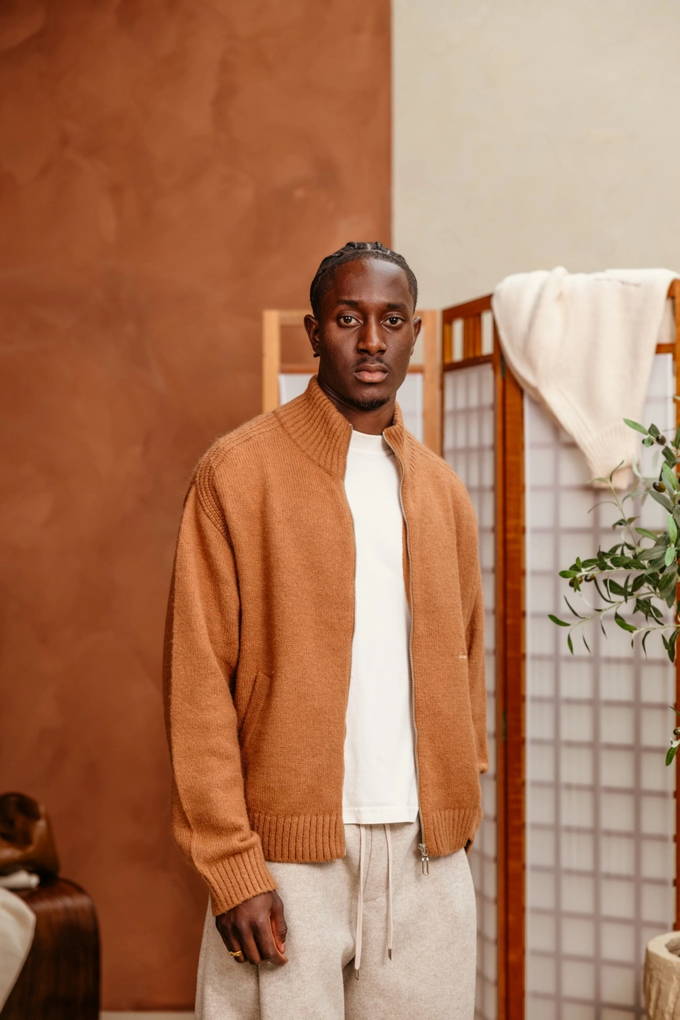 Camel zip-up cardigan on a male model in the warm studio