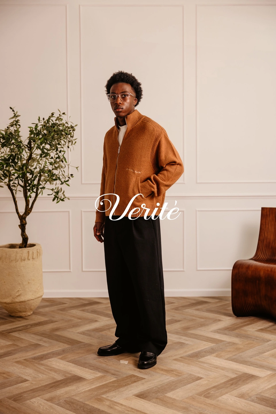Camel zip-up cardigan on a male model with the VERITÉ wordmark